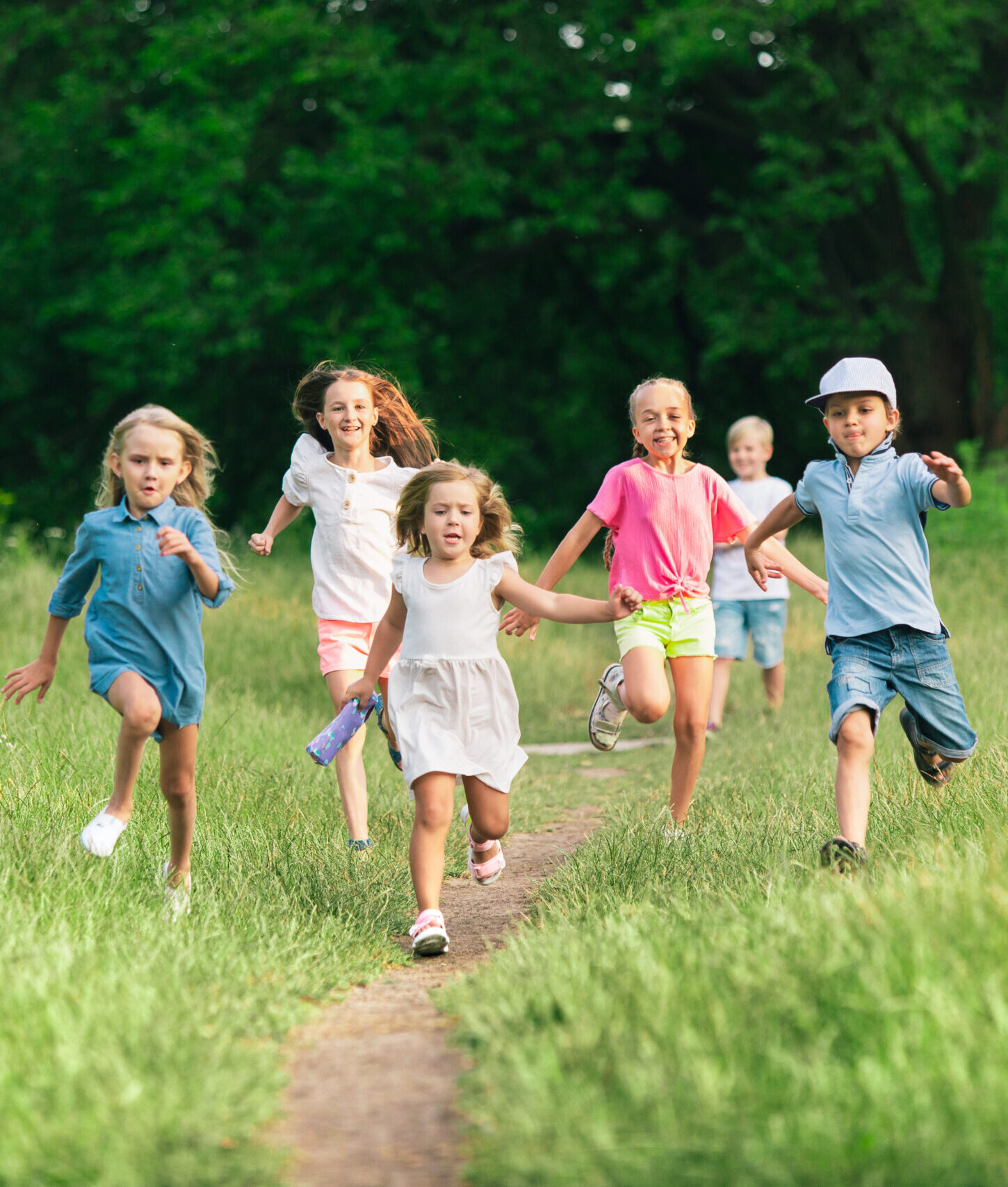 Kids, children running on meadow in summer's sunlight. Look happy, cheerful with sincere bright emotions. Cute caucasian boys and girls. Concept of childhood, happiness, movement, family and summer.