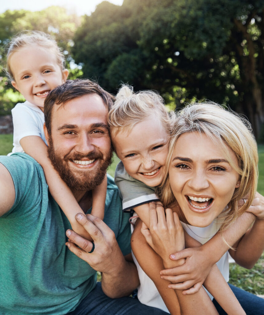Nature, selfie and portrait of a happy family on a picnic together in outdoor green garden. Happy, smile and parents playing, hugging and bonding with children outside in backyard or park in canada