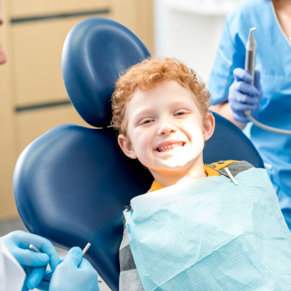 Portrait of a happy young boy with smile sitting on the dental office