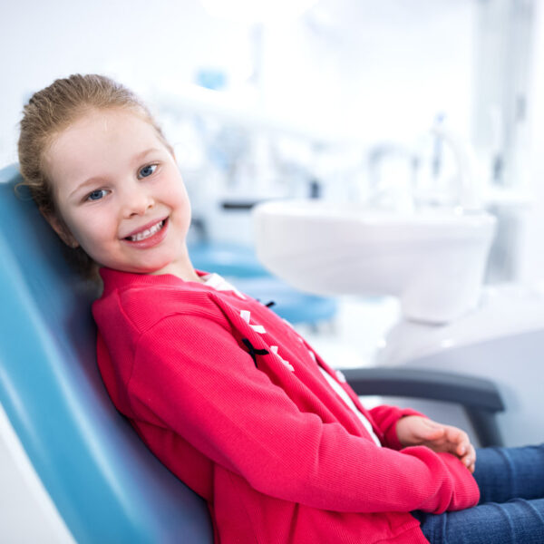Beautiful smiling little girl in dental office, waiting for dental treatment