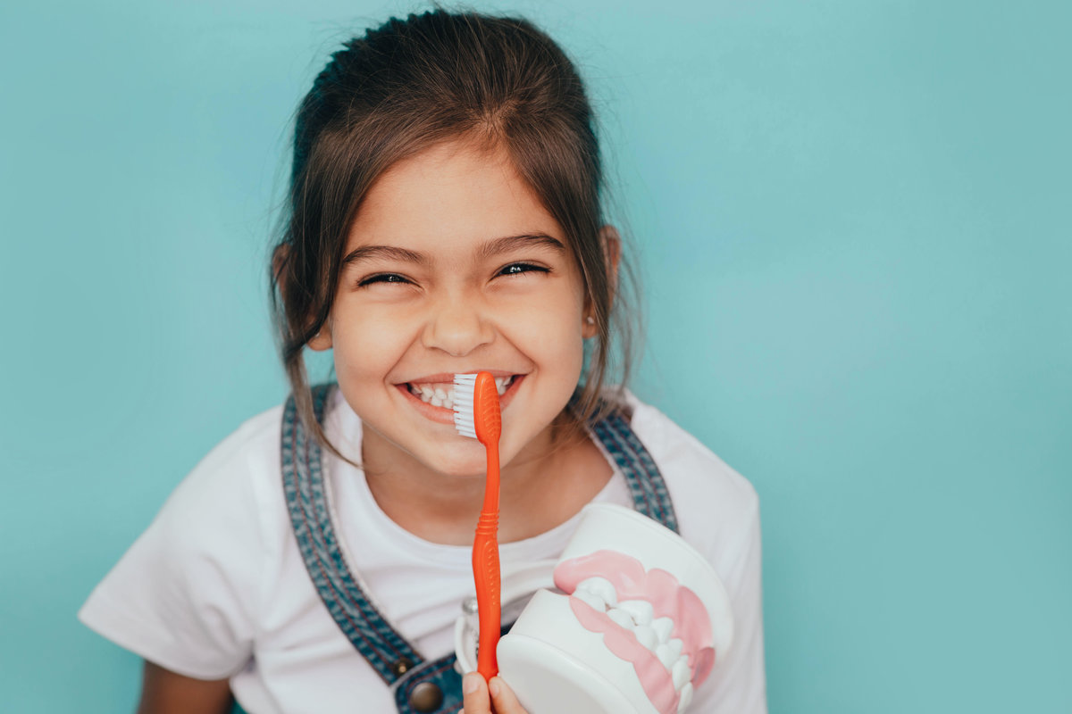 Yes, my teeth is clean. Cute mixed raced girl brushing teeth at blue background.