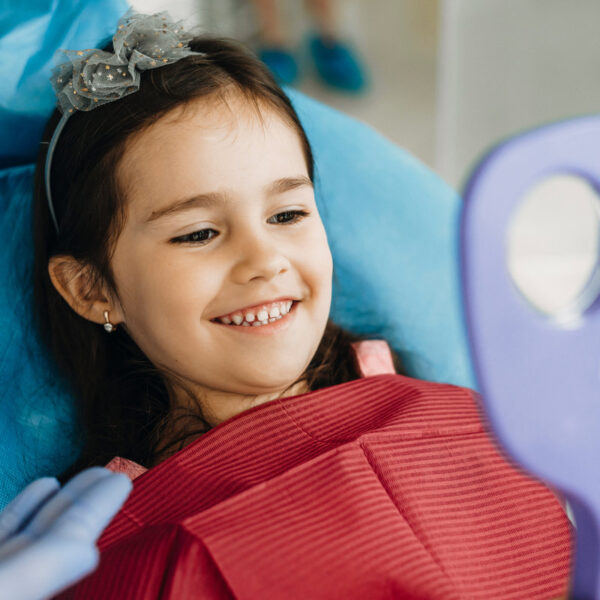 Happy little kid looking in the mirror after teeth examination in a pediatric stomatology.