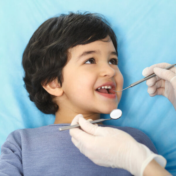 Little baby girl sitting at dental chair with open mouth during oral check up while doctor. Visiting dentist office. Medicine concept.