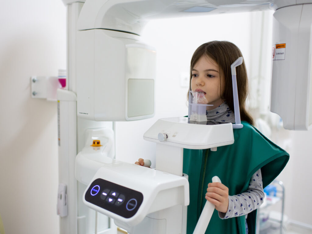 medicine, dentistry and healthcare concept. x-ray machine scanning kid patient teeth at dental clinic