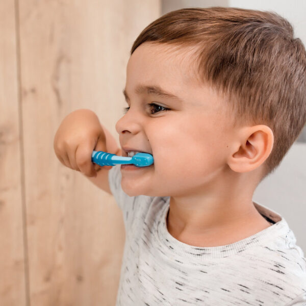 Little baby boy having fun brushing his teeth in modern bathroom on sunny morning. Dental hygiene and health for children.