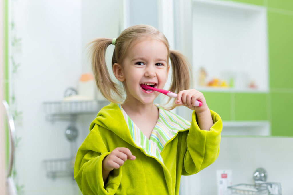 Little kid girl brushing teeth in bathroom