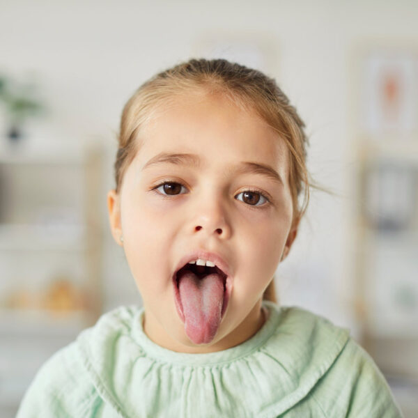 Portrait of a girl patient showing tongue for a dental or throat inspection during a healthcare checkup in a clinic. Dentistry and healthcare services focus on thorough medical examination.