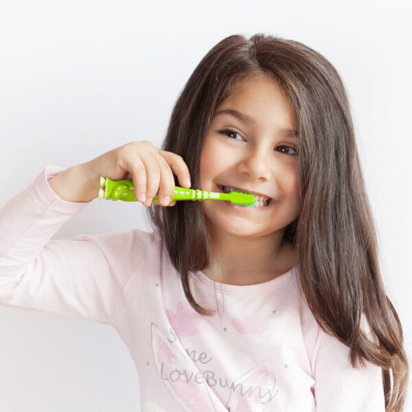 Little cute child girl brushing her teeth on white background. Space for text. Healthy teeth.