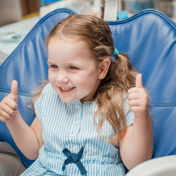 Little girl sitting on dental chair . milk teeth care concept. Dentist examining girl's teeth in clinic..