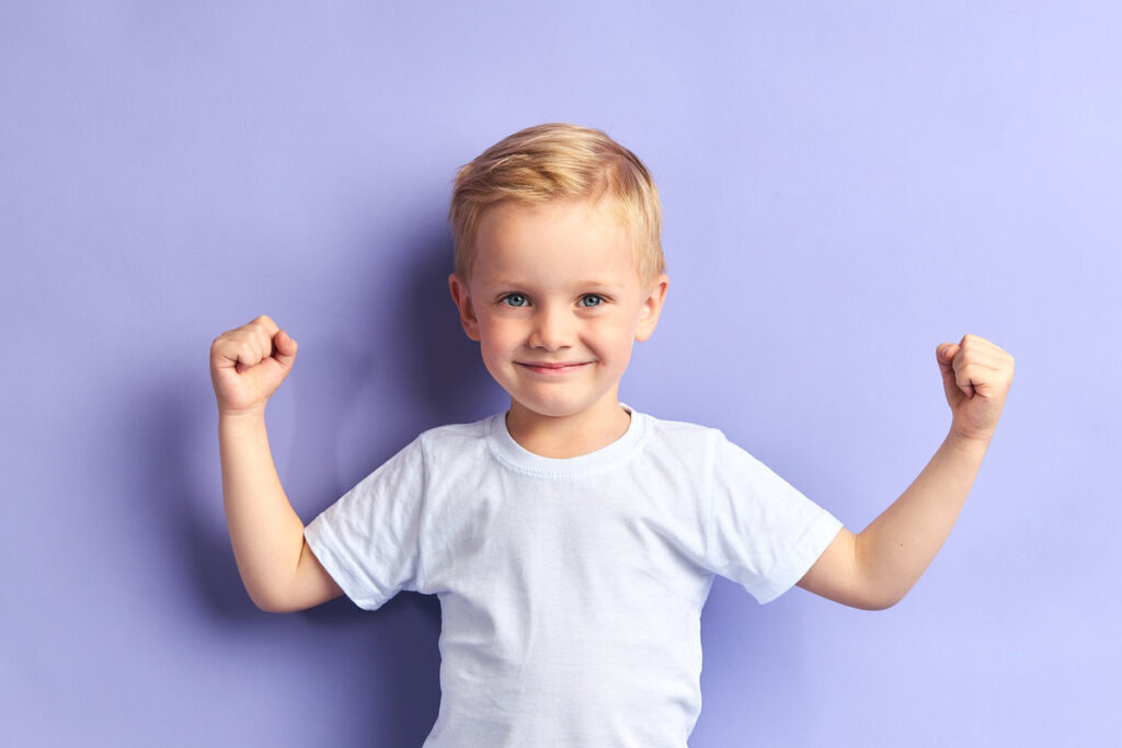 Winner kid isolated over purple background, show how powerful he is. Isolated over purple background