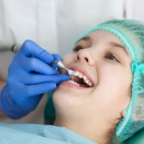 A woman dentist doctor brushes the teeth of a teenage child with a special medical brush. Inspection of the oral cavity of the girl. Modern technologies in dentistry.
