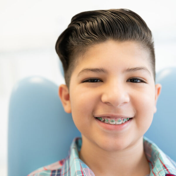 Closeup portrait of smiling cute Latin boy wearing braces in a dental clinic