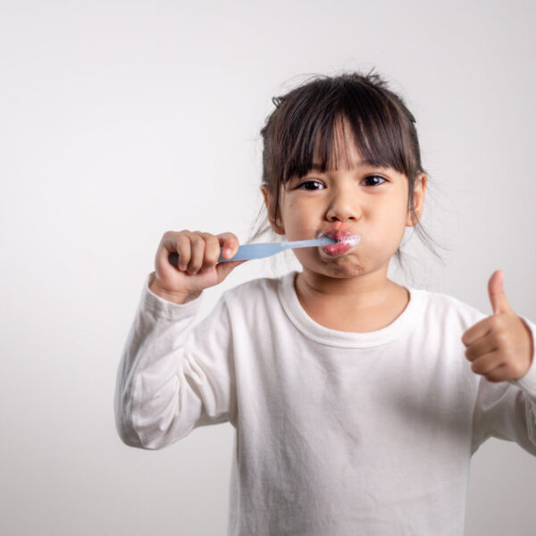 Little cute baby girl cleaning her teeth with toothbrush on white background