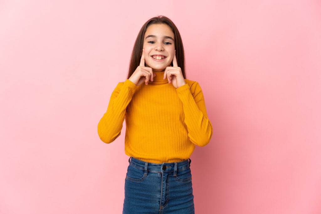 Little girl isolated on pink background smiling with a happy and pleasant expression