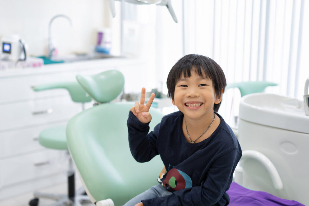 The Asian boy feel happy to sit on the dental chair in dental clinic