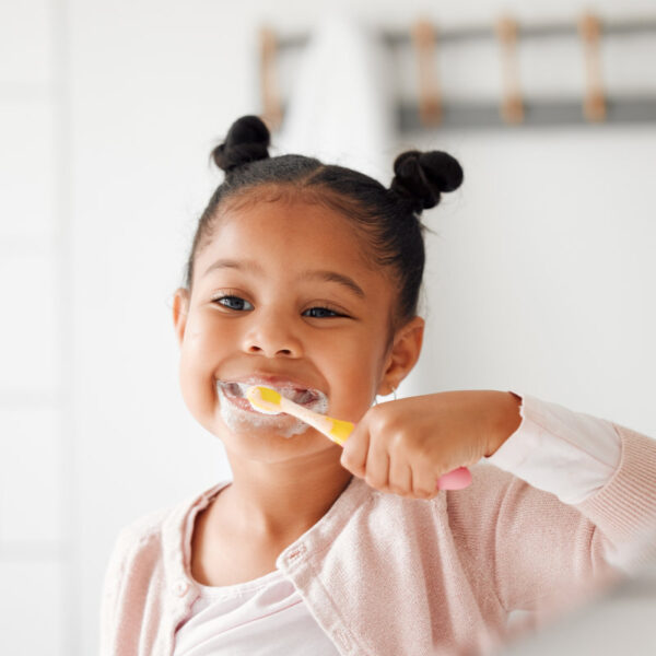 Toothbrush, brushing teeth and child in a home bathroom for dental health and wellness. Face of african girl kid cleaning mouth with a brush in a mirror for morning routine and oral self care.