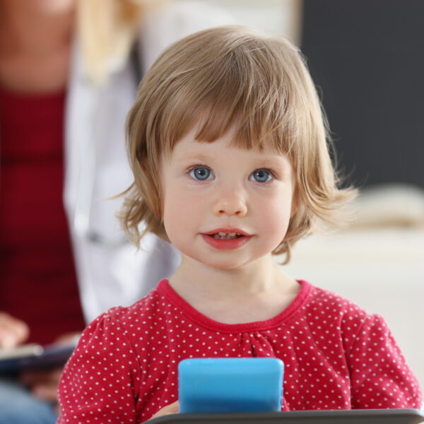 Portrait of little girl on background of doctor in white coat. Child examination and medical care concept