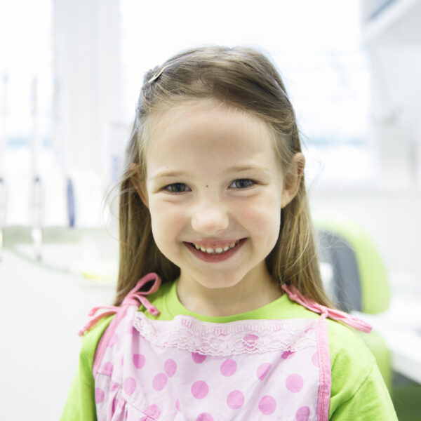 Relaxed little girl at dental office, smiling and waiting for a checkup. Early prevention, paedodontics and no fear concept.