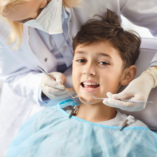 Dentist in the clinic examines a smiling boy, close-up. At the doctor, the child opened his mouth to examine his teeth. Concept dental health in adolescents, dental hygiene , tooth decay