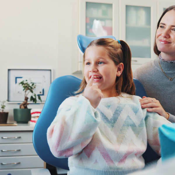 Child, dentist and show tooth at dental consultation with orthodontist for advice or cleaning. Happy girl, family or woman in clinic for gum care, wellness and learning about oral hygiene and health.
