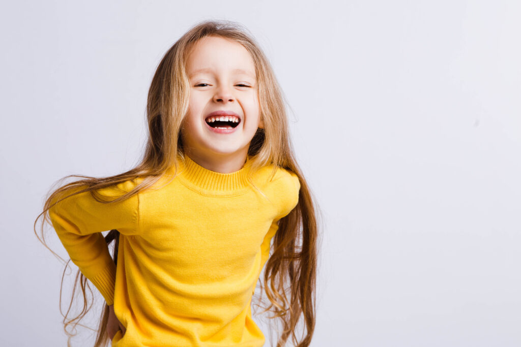 Cute girl 4-5 year old in a yellow sweater posing in studio. Original, square photo with space for text.