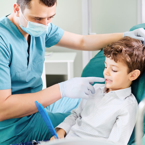 Boy child and dentist are checking teeth in the mirror in the dental clinic.