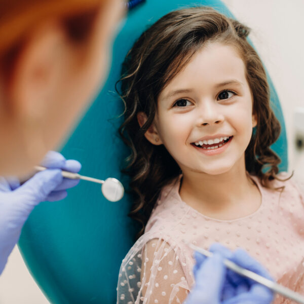 Lovely little kid smiling while talking with the pediatric dentist after doing a tenth examination in a pediatric stomatology.