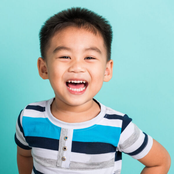 Asian portrait of cute little boy kid happy face he laughing smiles and looking to camera, studio shot isolated on blue background