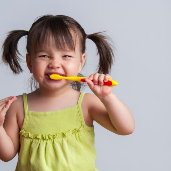Toddler smiling while brushing her teeth