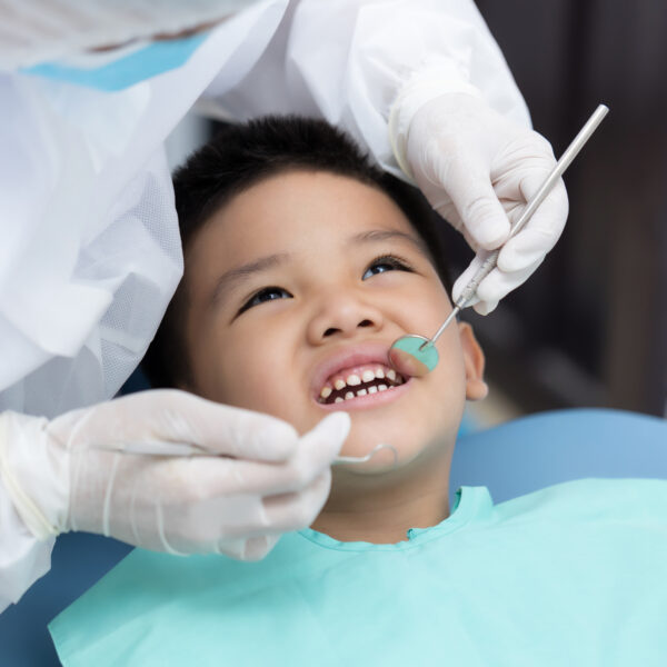 Dentist examining Asian little boy teeth in clinic.
