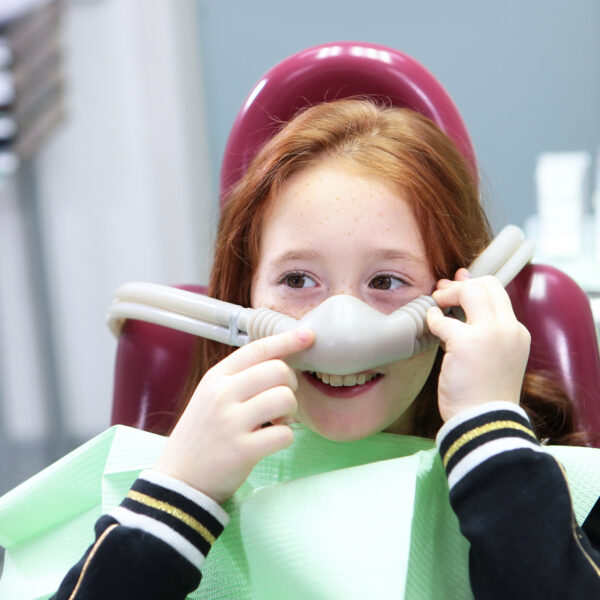 Little girl with sedation mask. Treatment of children's teeth with nitrous oxide. Anesthesia for children in dental treatment. Children's dentistry.