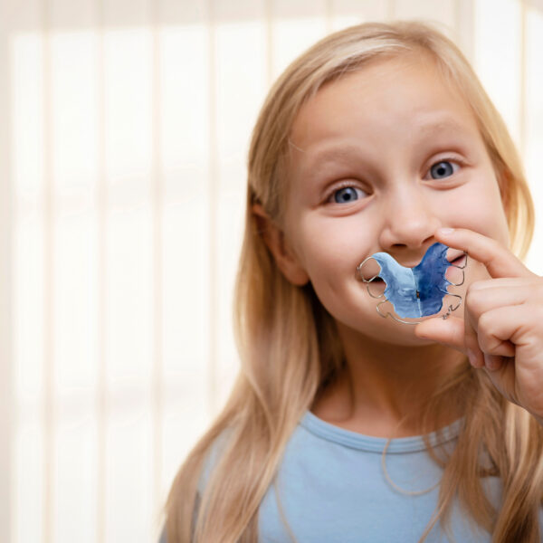 Retainer for Expansion Jaw of Children. Happy Child Little Girl holding Orthodontic Plate Teeth in Hands. Dental plate. Copy space.