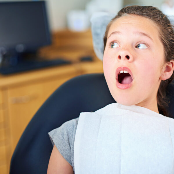 Dental, wow or scared girl in consultation room with phobia, worry or fear for dentist exam. Orthodontics, stress or teen person nervous for teeth, cavity or bacteria, risk or gum disease emergency.