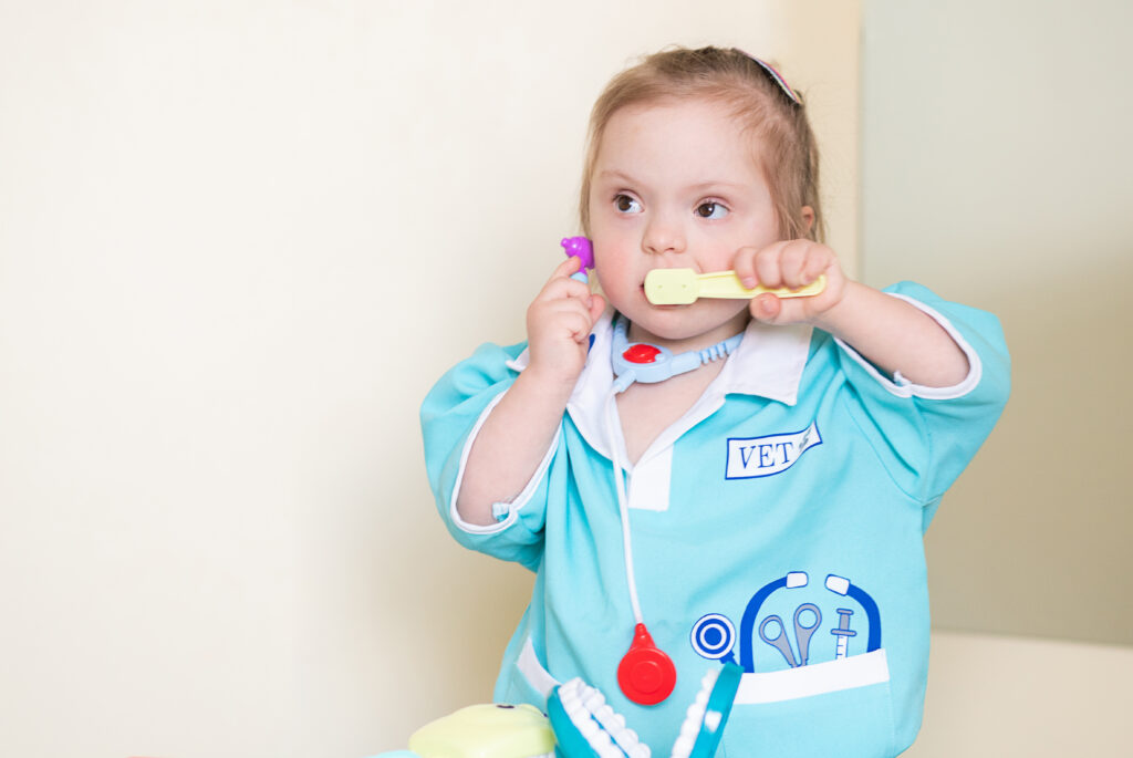 A young girl with Down syndrome playing with a plastic toy medical kit. Promoting child development through play, she explores various medical tools, fostering creativity and learning.