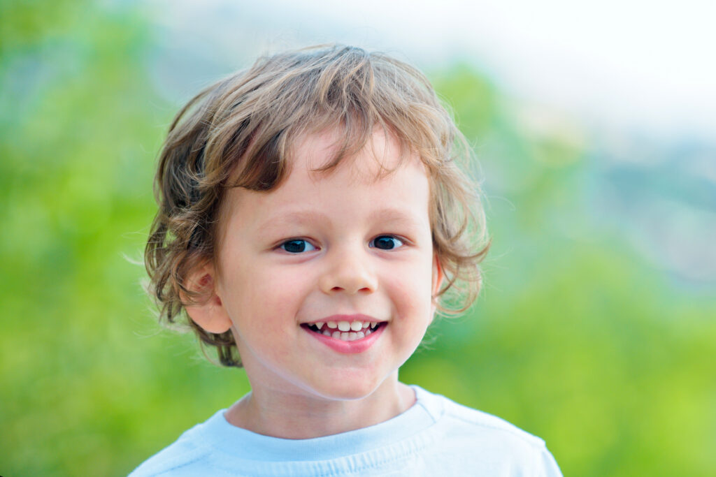 Emotional kid walks outdoors and enjoy walking. Portrait of a boy smiling. Has happy. Funny boy. Happy toddler boy in the park. Little cute kid is smiling. Emotions on the face. Copy space