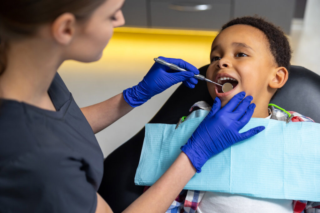In dentistry. Female doctor checking up dark-skinned boy