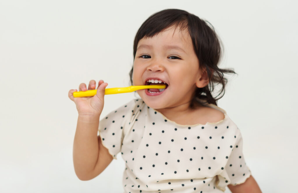 happy toddler girl brushes her teeth with a smile